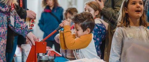 A child pulls down on a large stamp with other children around