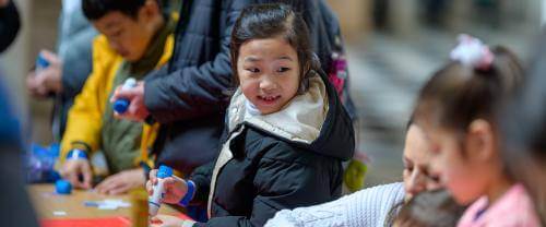 Children using glue in a craft activity at a table